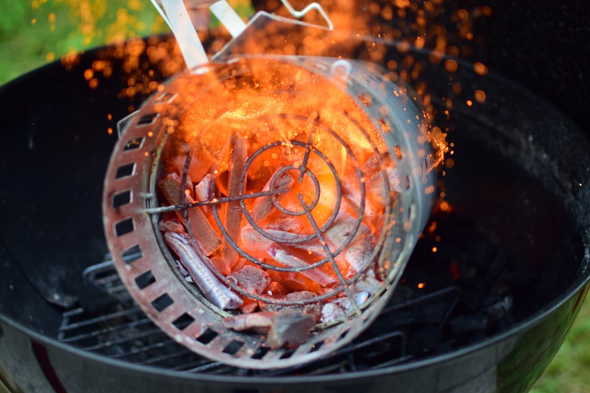 Pouring hot coals from a charcoal chimney into a kettle grill. Much better than using lighter fluid.